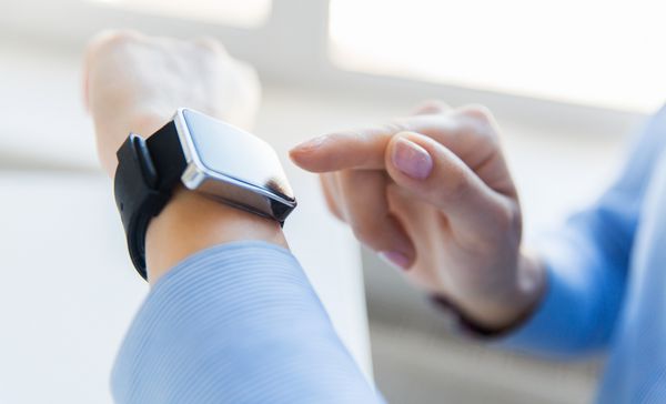 مفهوم کسب و کار فناوری و مردم - از نزدیک دست های زن که ساعت هوشمند را در دفتر تنظیم می کند