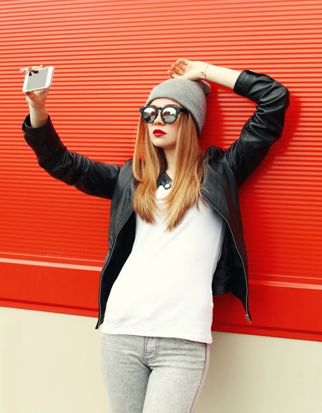 دختر باحال هیپستر مد در حال گرفتن عکس از خود با گوشی هوشمند در شهر