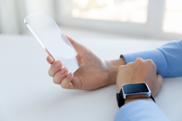 مفهوم کسب و کار فناوری و مردم - نمای نزدیک از دست زنی که تلفن هوشمند و ساعت شفاف را در دفتر گرفته و نشان می دهد