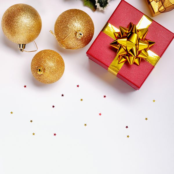 دکوراسیون کریسمس جدا شده سفید جعبه های هدیه قرمز و طلایی با سه توپ طلایی و تزئینات گل نمای بالا ترکیب مربع