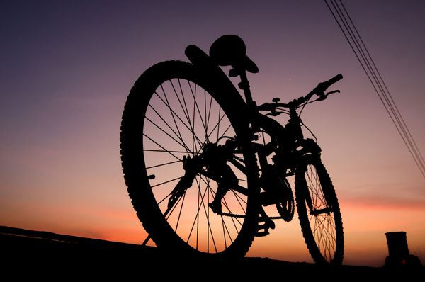 شبح پارک دوچرخه کوهستان در اسکله کنار دریا با پس زمینه آسمان غروب خورشید