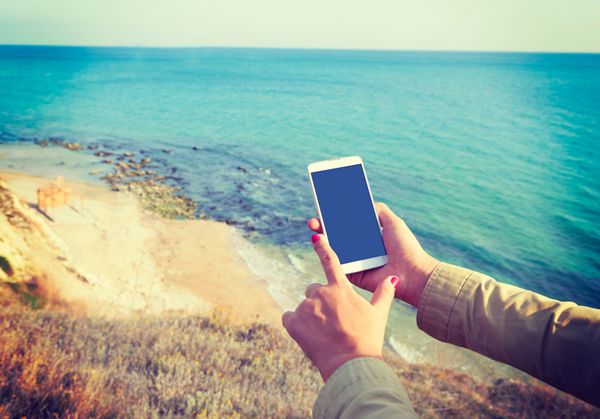 تلفن هوشمند سفید در پس زمینه دریای سیاه در دستان زن افکت اینستاگرام