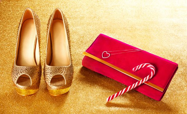 خرید کریسمس کفش طلا و کیف قرمز عصا آب نبات در زمینه کاغذ طلایی زن حاضر