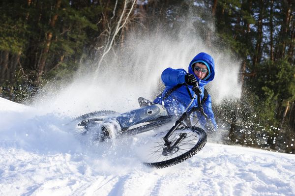 دوچرخه سوار افراطی دوچرخه سواری کوهستان در پرواز برف در نزدیکی جنگل زمستانی در روز سرد آفتابی