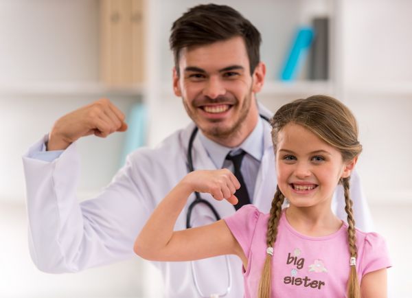 پزشک اطفال شاد و خندان و دختری که دستان خود را نشان می دهد در بیمارستان