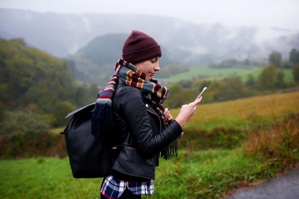 زن سرگردان جوان جستجوی موقعیت در تلفن همراه برای یافتن راه درست در طول تور ماجراجویی در کوهستان زن کوهنورد هنگام بالا رفتن از کوه پیش بینی آب و هوا را از طریق تلفن همراه بررسی می کند