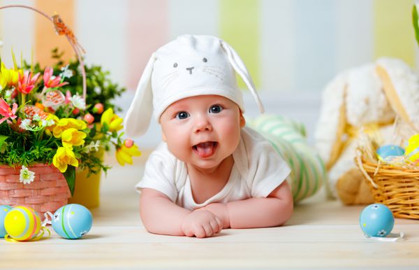 کودک مبارک با گوش های خرگوش عید پاک و تخم مرغ و گل های رنگارنگ