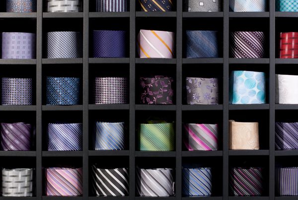پس‌زمینه فوق‌العاده مجموعه‌ای از کراوات‌های چند رنگ در یک محیط خرده‌فروشی