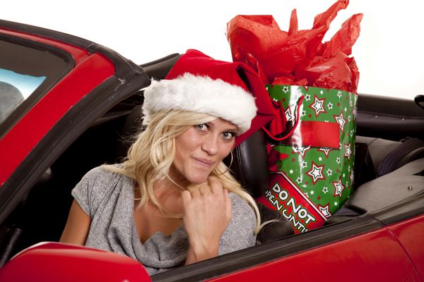 زنی در حالی که کلاه بابا نوئل خود را با هدیه ای در صندلی عقب خود بر سر دارد به بیرون نگاه می کند