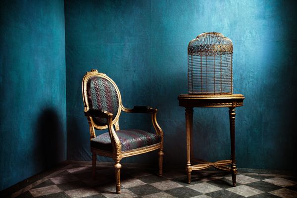 میز لوئیس صندلی راحتی و قفس طلایی قدیمی پرنده در اتاق آبی با کف کاشی