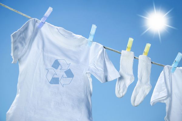 خشک کردن لباس های دوستدار محیط زیست روی خط لباس در مقابل آسمان آبی با خورشید