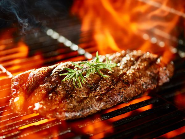 پخت استیک آهنی تخت روی گریل شعله ور با تزئین رزماری