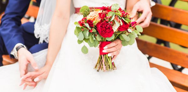 گل عروسی زنی که دسته گل رنگارنگ را در روز عروسی با دستانش نگه داشته است