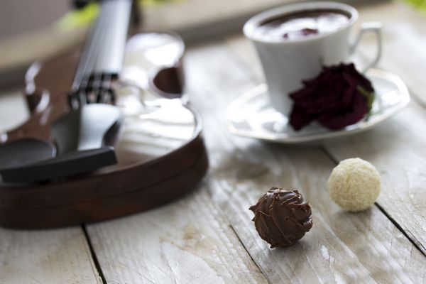 قهوه ترک شکلات ترافل ویولن و رز قرمز خشک شده روی میز چوبی