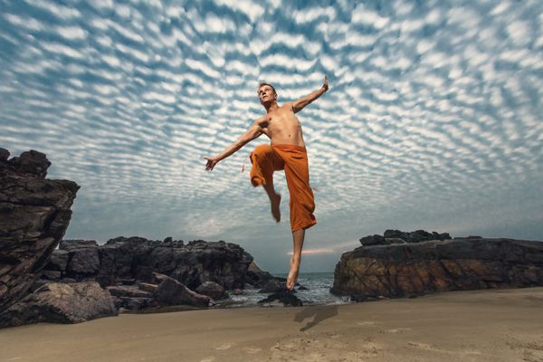 مرد جوان در حال پریدن از ارتفاع در ساحل