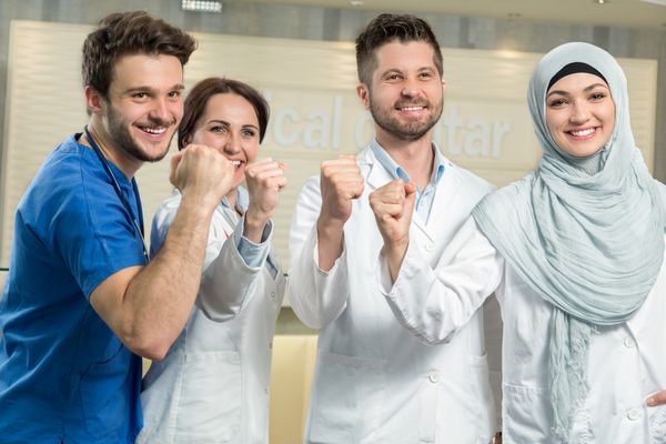 مفهوم مراقبت های بهداشتی و پزشکی - پزشک مرد جذاب در مقابل گروه پزشکی در بیمارستان که شست را نشان می دهد