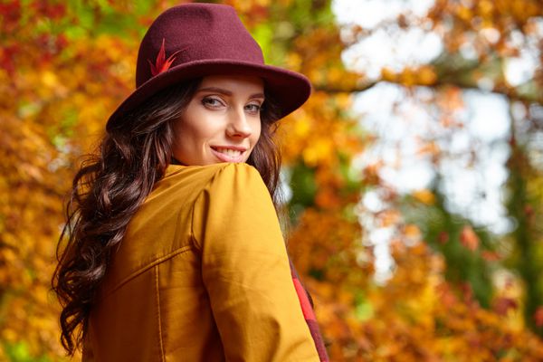 سن زن جوان زیبا در پارک پاییزی با کلاه قهوه ای رنگ