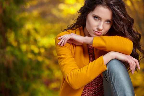 زن جوان زیبا در یک ظاهر طراحی پاییزی در پس زمینه aut