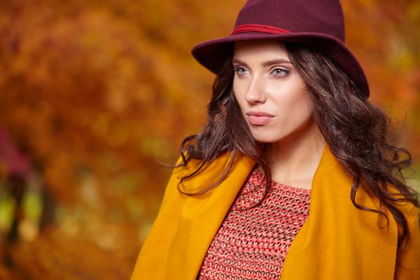 سن زن جوان زیبا در پارک پاییزی با کلاه قهوه ای رنگ