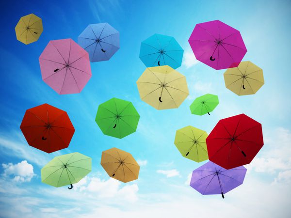 چترهای چند رنگ در برابر آسمان آبی تصویر سه بعدی