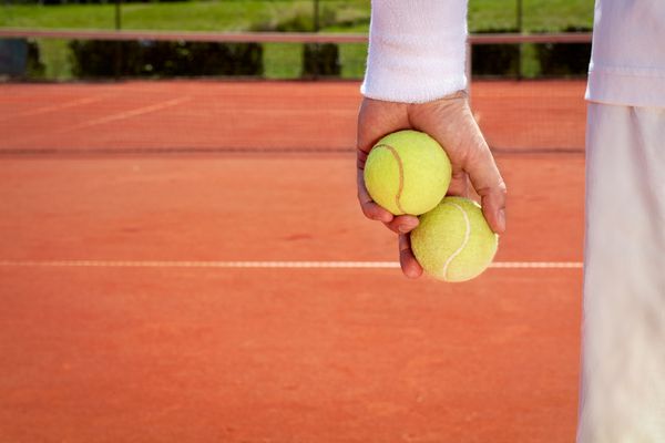 نمای نزدیک از توپ های تنیس در دست ورزشکار