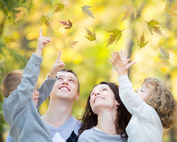 خانواده شاد در حال تفریح در فضای باز در پارک پاییز در برابر پس زمینه برگ های تار