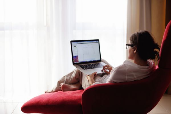 زن جوان زیبا با استفاده از کامپیوتر لپ تاپ در خانه