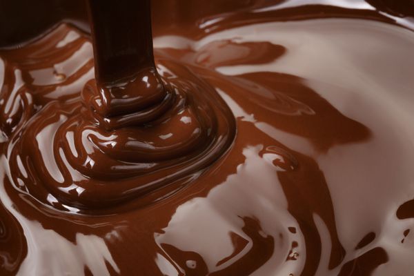 جریان شکلات تلخ ذوب شده آب نبات یا پس زمینه آماده سازی شکلات