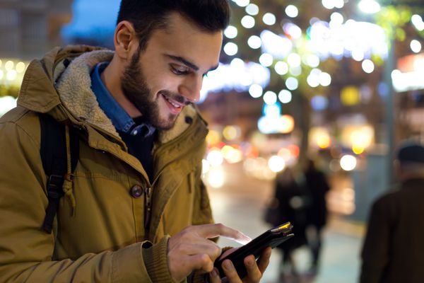پرتره مرد جوان در فضای باز با استفاده از تلفن همراه خود در شب