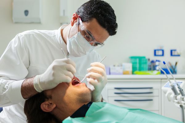 دندانپزشک مرد اروپایی در حال انجام معاینه یک مرد 40 ساله
