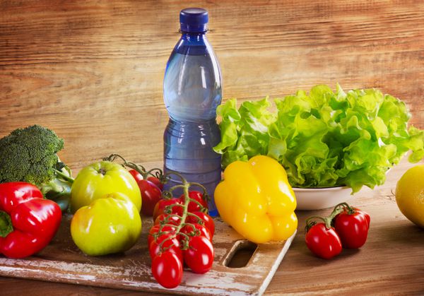 سبزیجات و میوه های ارگانیک تازه با بطری آب - مفهوم سلامت و رژیم غذایی