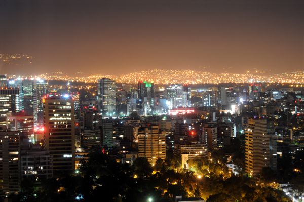 خط افق شهر مرکز شهر مکزیک در شب با نورهای روشن حومه شهر در پس زمینه