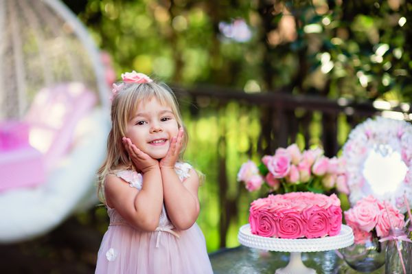 دختر کوچک جشن تولدت مبارک با دکور گل رز در باغ زیبا
