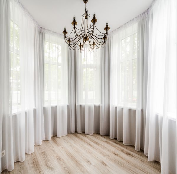 داخلی اتاق زیبا با کف چوبی پرده سفید و لوستر