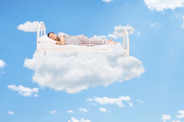 مردی که روی تختی در ابرها در بالای آسمان خوابیده است