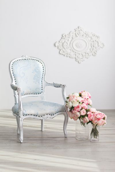 صندلی راحتی آبی روشن و گلهای ظریف در نزدیکی دیوار سفید داخلی در رنگ های سفید