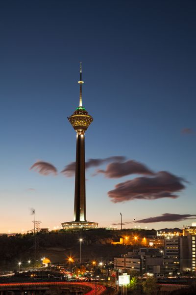برج میلاد نورانی در خط افق تهران در هنگام غروب در برابر آسمان آبی ابری