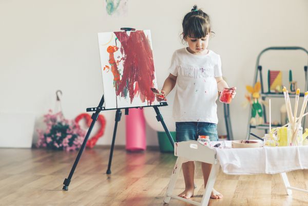 دختر ناز کوچکی که در خانه اش نقاشی می کند فوکوس انتخابی و عمق میدان کم
