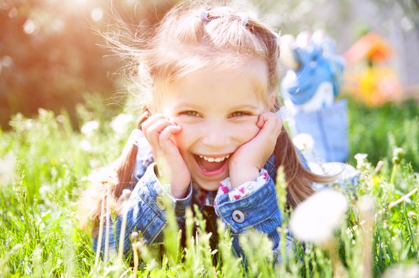 دختر کوچولوی ناز در حال لبخند زدن در نمای نزدیک پارک