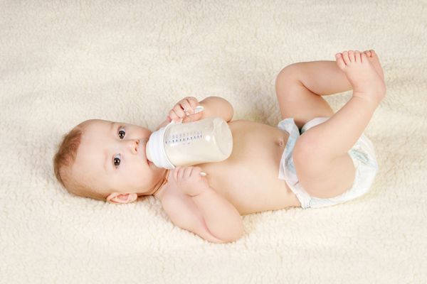 کودک 8 ماهه یک ترکیب لبنی را از یک بطری کوچک می نوشد