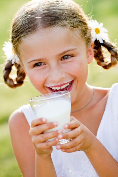 سلامتی رژیم غذایی - دختر دوست داشتنی در حال نوشیدن شیر تازه در فضای باز