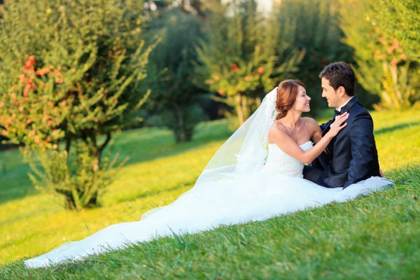 عروس زیبا با یک داماد خوش تیپ در کنار هم خوشحال هستند