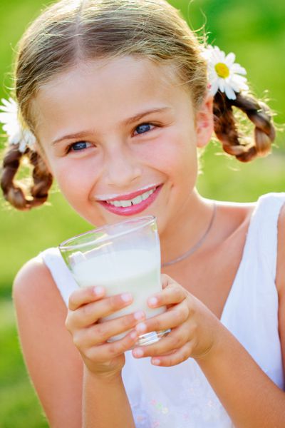 سلامتی رژیم غذایی - دختر دوست داشتنی در حال نوشیدن شیر تازه در فضای باز