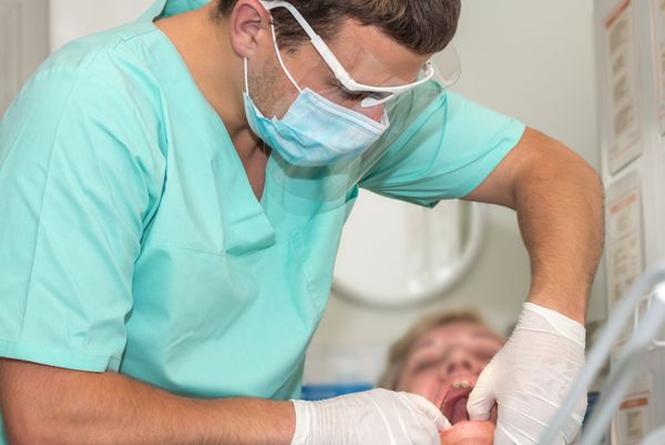 دندانپزشک جوانی که از دندان های یک زن مسن مراقبت می کند