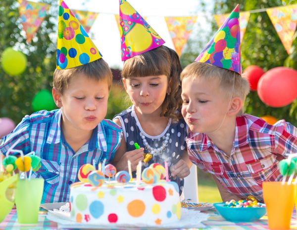 بچه ها در جشن تولد در حال شمع زدن روی کیک
