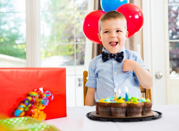 پسر تولد با کیک و هدیه روی میز