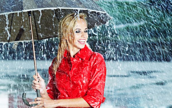 زنی زیبا که چتر را زیر باران نگه داشته است