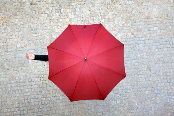 زن تاجر زیر چتر پنهان شده و چک می کند که آیا باران می بارد