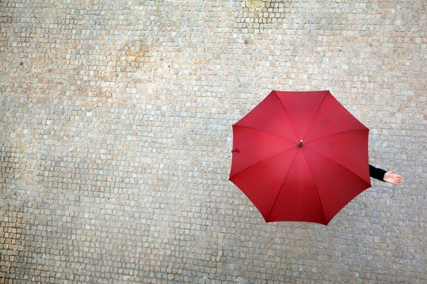 زن تاجر زیر چتر پنهان شده و چک می کند که آیا باران می بارد