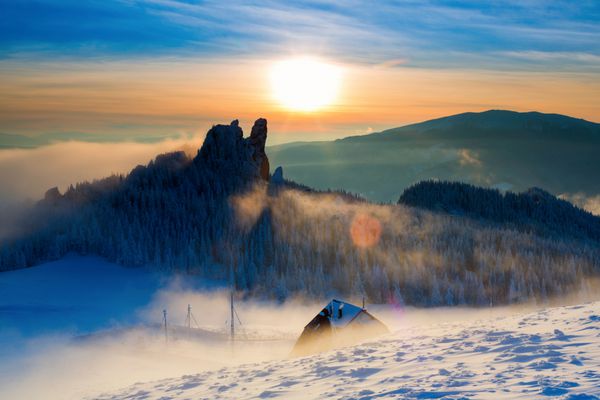 کابان در کوه زمستانی در غروب آفتاب با پس زمینه رنگارنگ